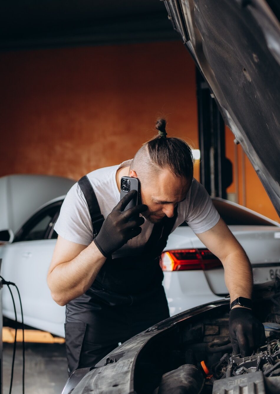 Auto mechanic talking on mobile phone in auto repair shop